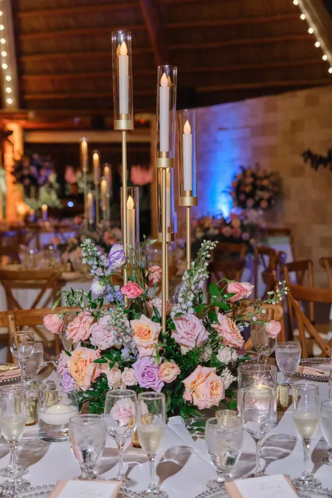 Blush flowers and gold taper candles decorate an evening reception table.