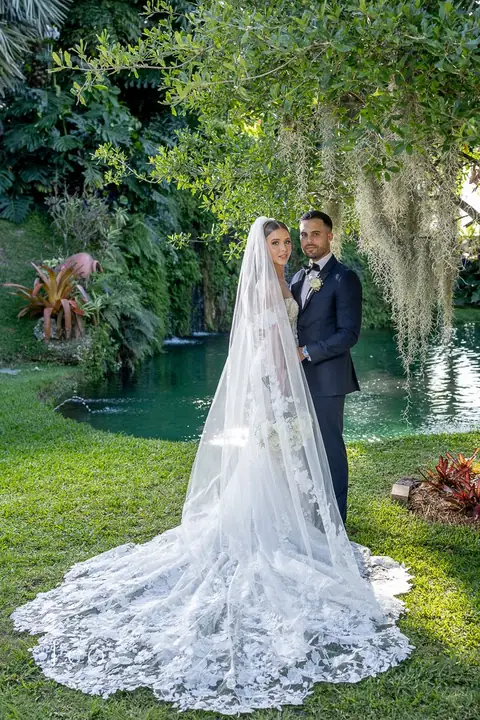 Newlyweds pose beside the pond under hanging Spanish moss.