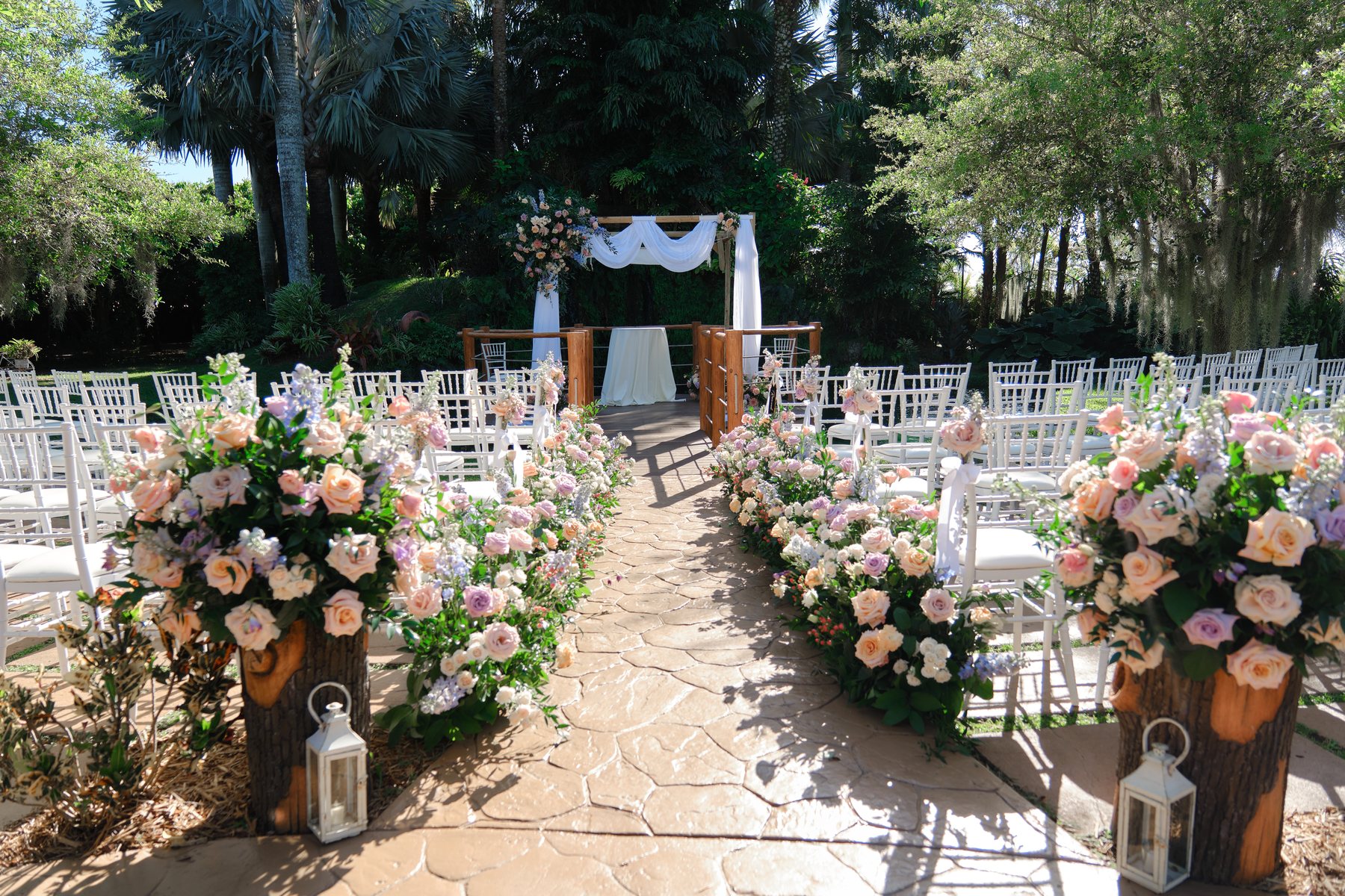 Floral-lined garden ceremony aisle with white chairs at Longan’s Place in Miami