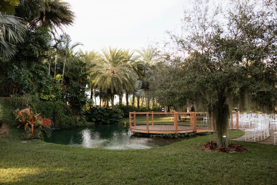Tropical garden, pond, wooden bridge, palms, and flowering landscaping at Longan’s Place in Miami