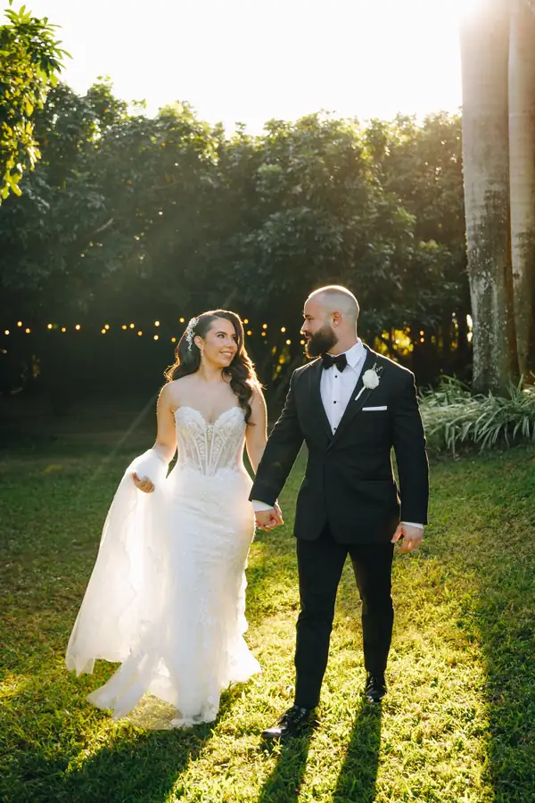 Newlyweds walking through the tropical garden at Longan’s Place in golden-hour sunlight