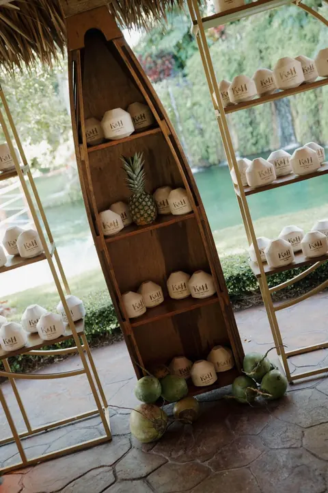 Personalized coconuts sit on wooden and gold shelves beside the pond.