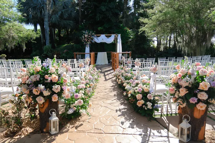 Pink floral arrangements line the outdoor garden ceremony aisle.